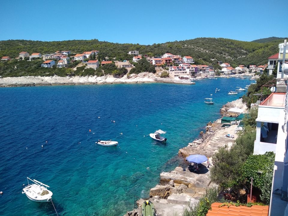 Coastal town with crystal-clear blue water and scattered small boats.