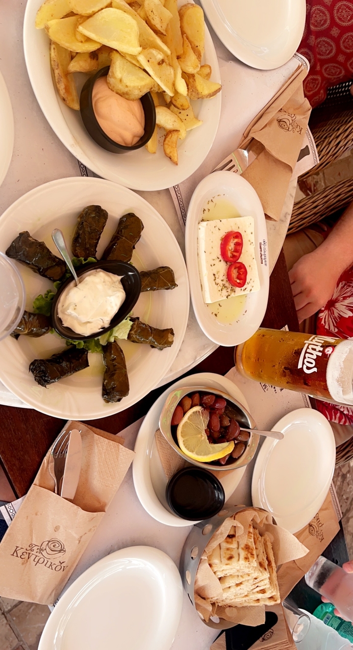 Assiette de feuilles de vigne, fromage feta, et un verre de bière sur une table.