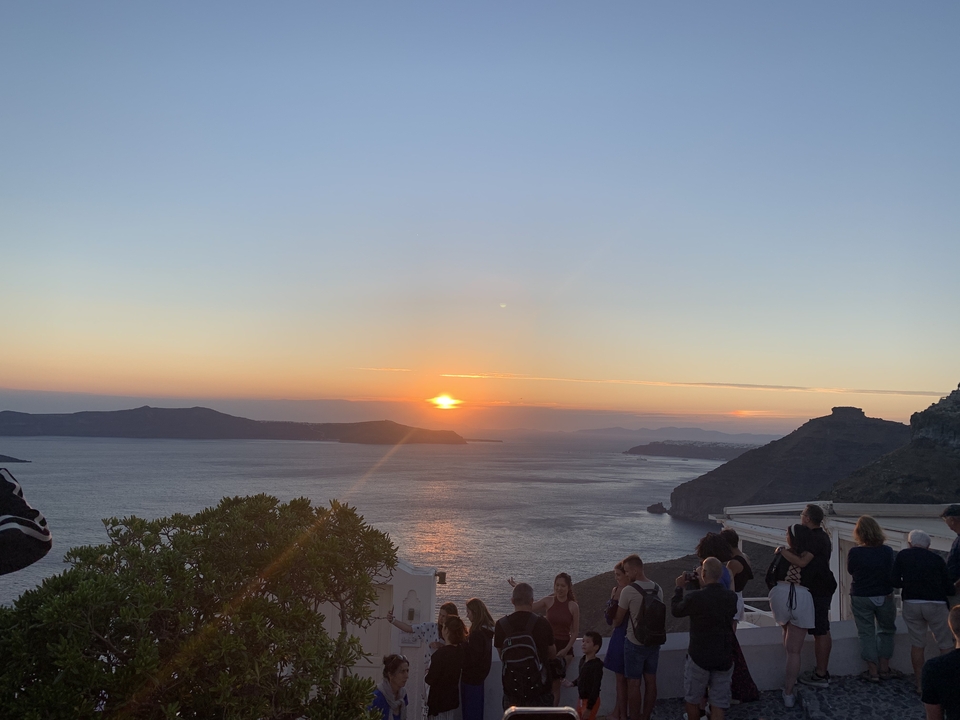 Sunset over the sea with mountains in the distance, possibly Santorini.