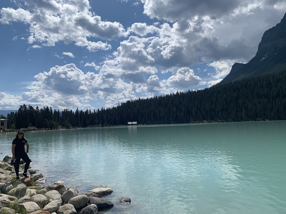 Lake surrounded by mountains with a person standing near the water