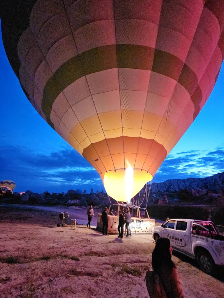 Montgolfière en cours de gonflage au lever du soleil.