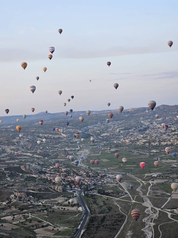 De nombreuses montgolfières flottant au-dessus d'un paysage à l'aube.