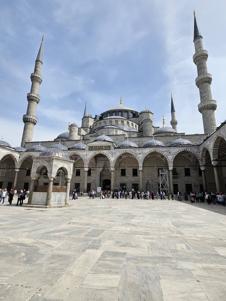 Cour de mosquée avec des gens qui se promènent.