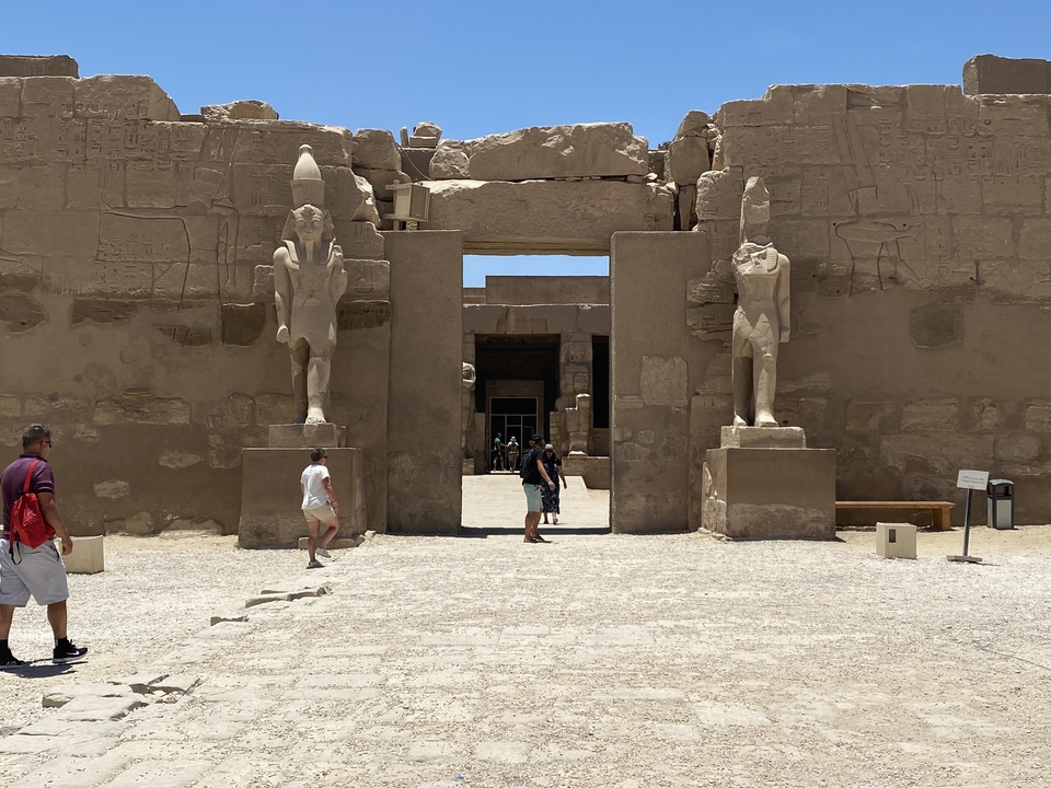 Des gens qui marchent à travers l'entrée d'un temple égyptien antique.