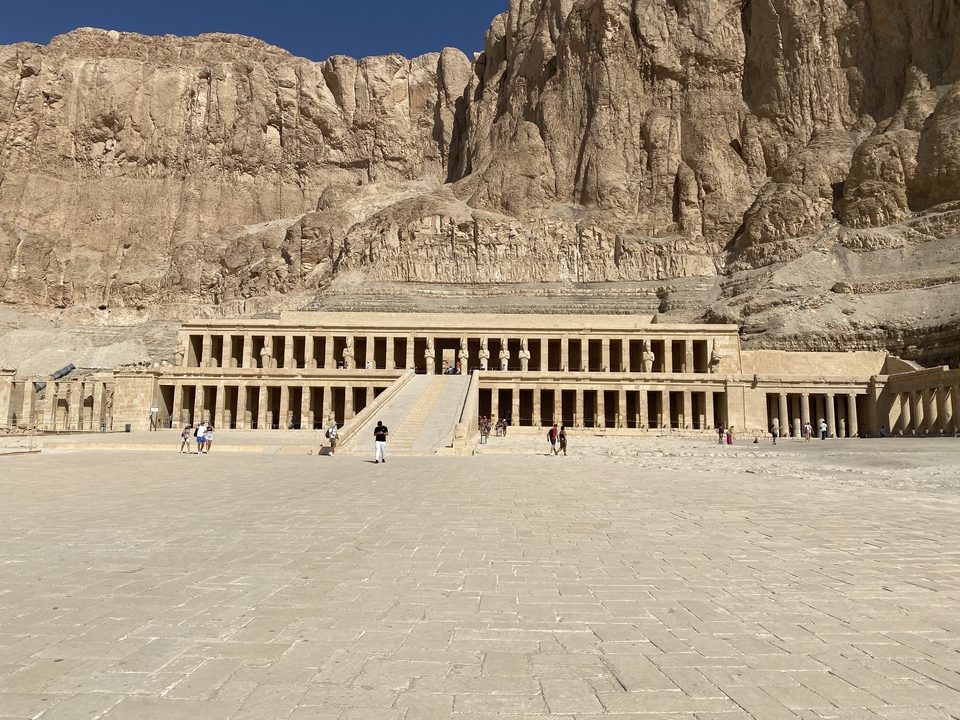 Temple d'Hatchepsout construit dans la falaise avec des touristes qui se promènent.