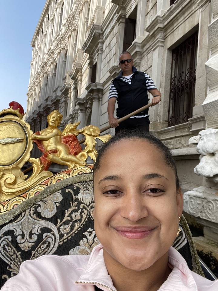 Selfie avec une personne dans une gondole et un gondolier qui rame sur une voie navigable.
