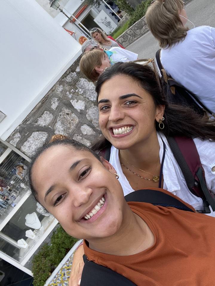 Groupe de personnes souriantes prenant un selfie avec des bâtiments en arrière-plan.