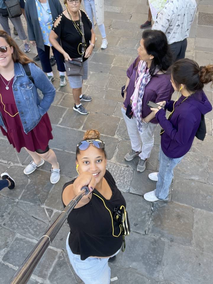 Des gens sur une place qui prennent un selfie de groupe avec une perche à selfie.
