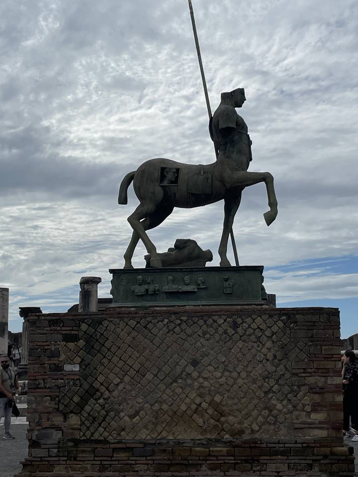 Statue représentant une figure à cheval contre un ciel nuageux.