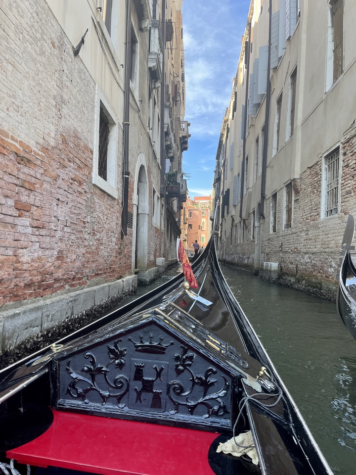Narrow canal with gondolas passing by
