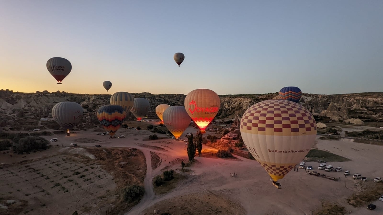 Montgolfières s'élevant au lever du soleil au-dessus de formations rocheuses.