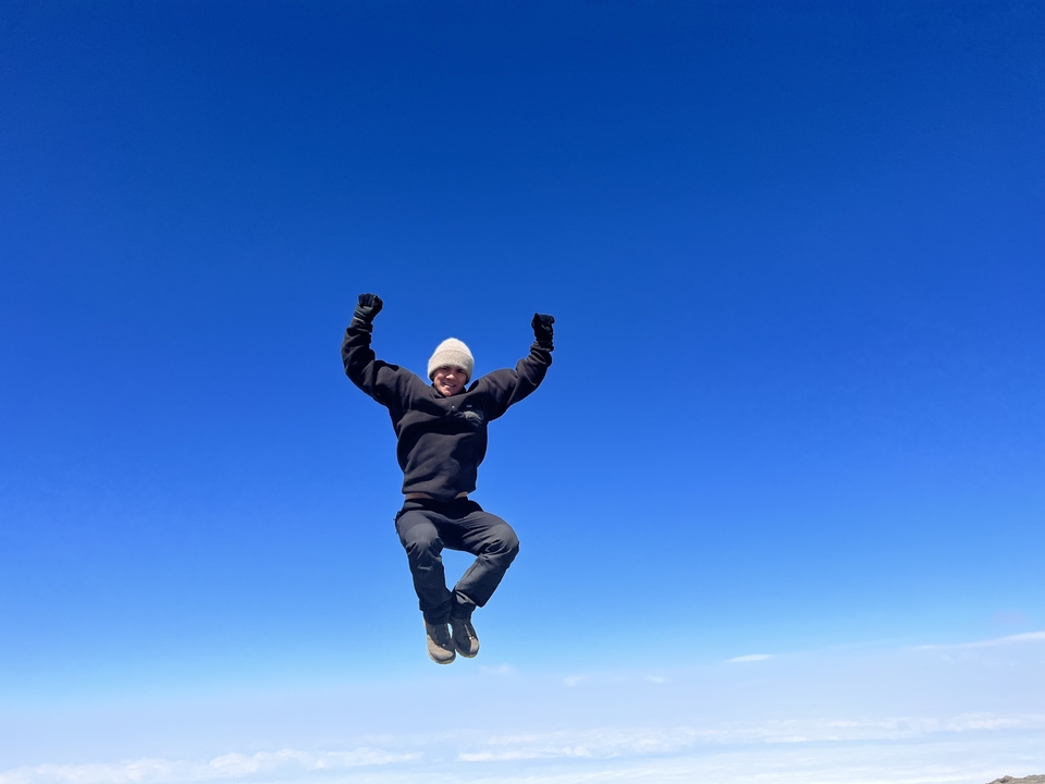 Person jumping in front of a clear blue sky.