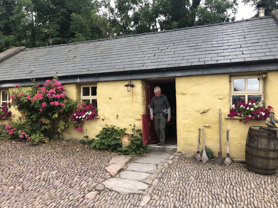 Person standing at the door of a countryside cottage.