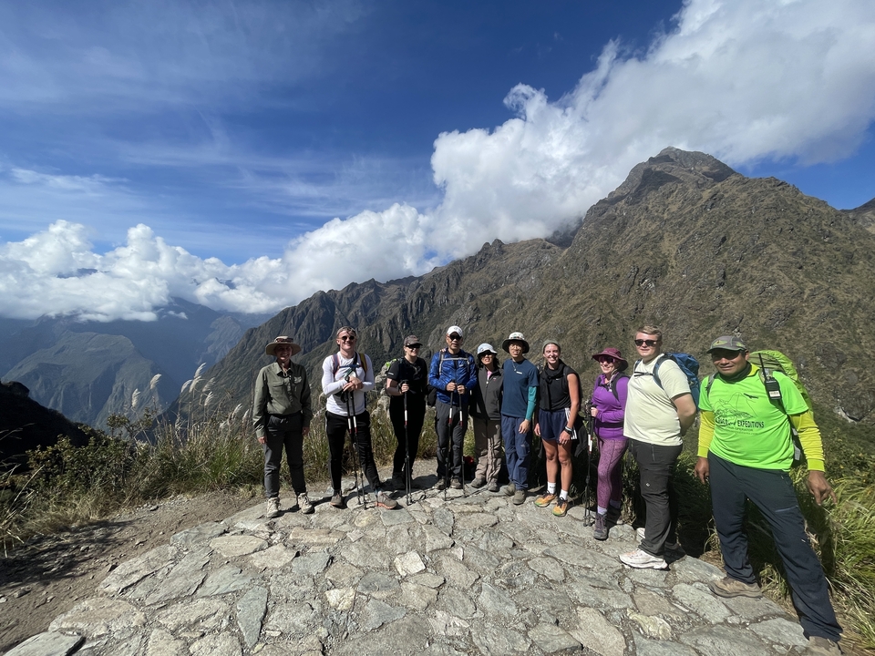Group of hikers posing with mountains in the background.