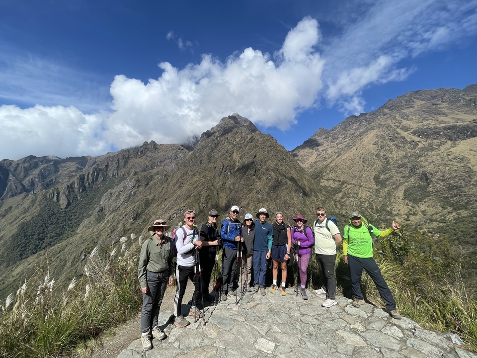Group of hikers posing with mountains in the background.
