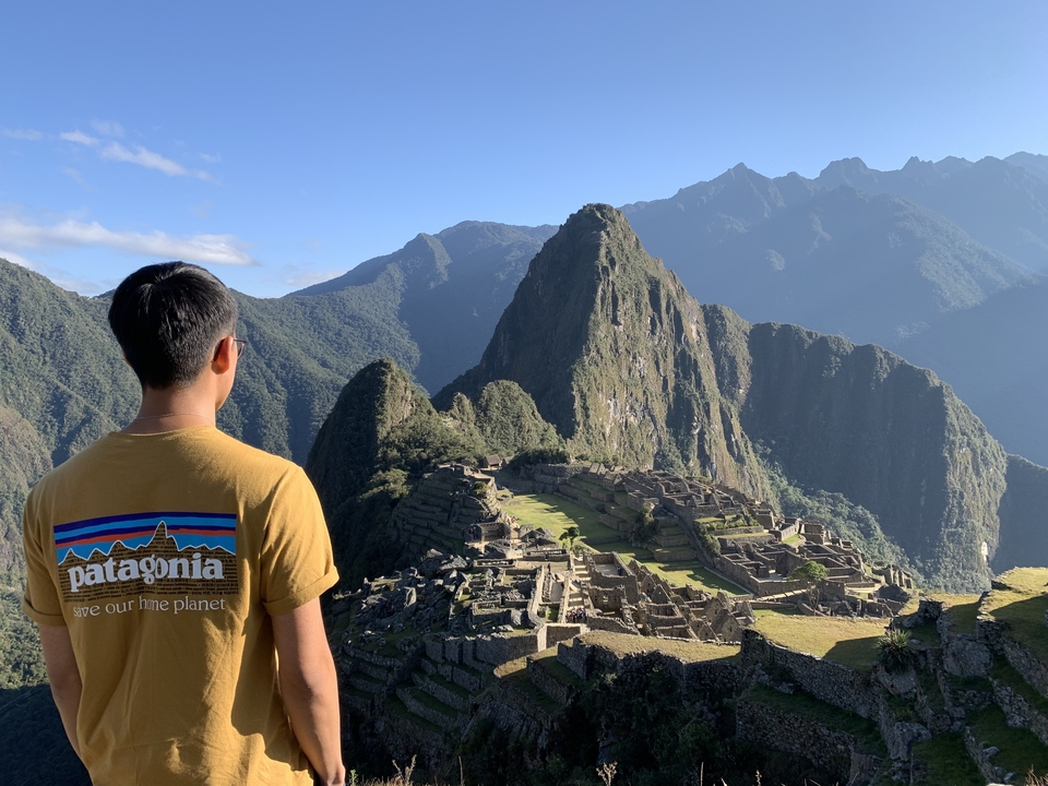 Person overlooking the ruins of Machu Picchu with mountains in the background.