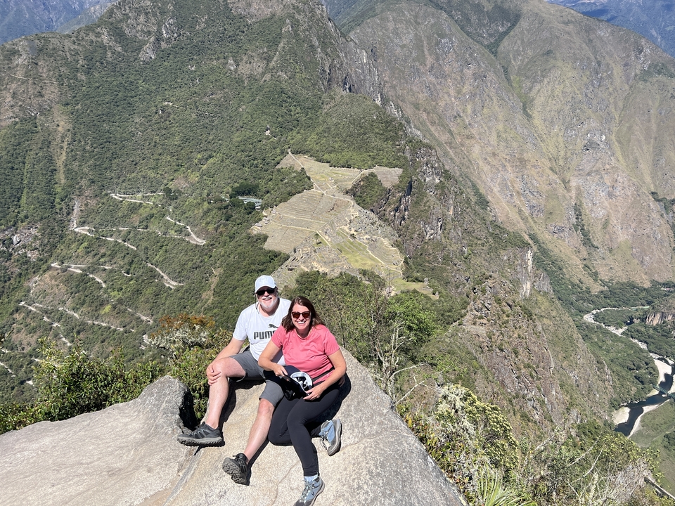Couple seated on a rock with a view of Machu Picchu in the background.