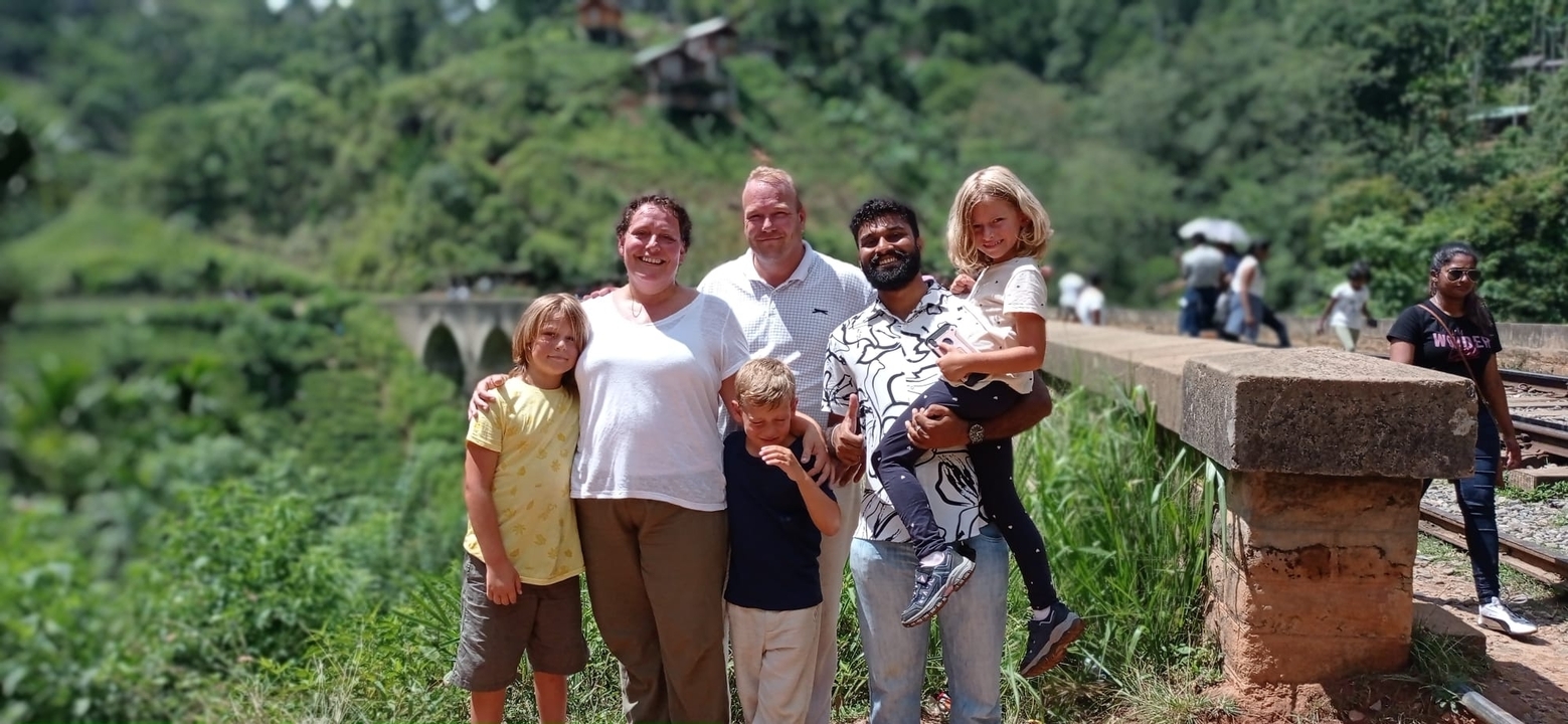 Family posing on a bridge with scenic background.
