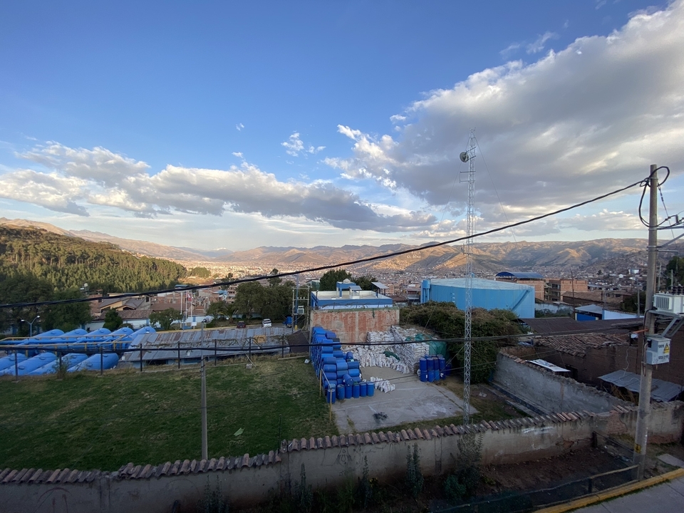 A cityscape with blue water tanks and mountains in the background.