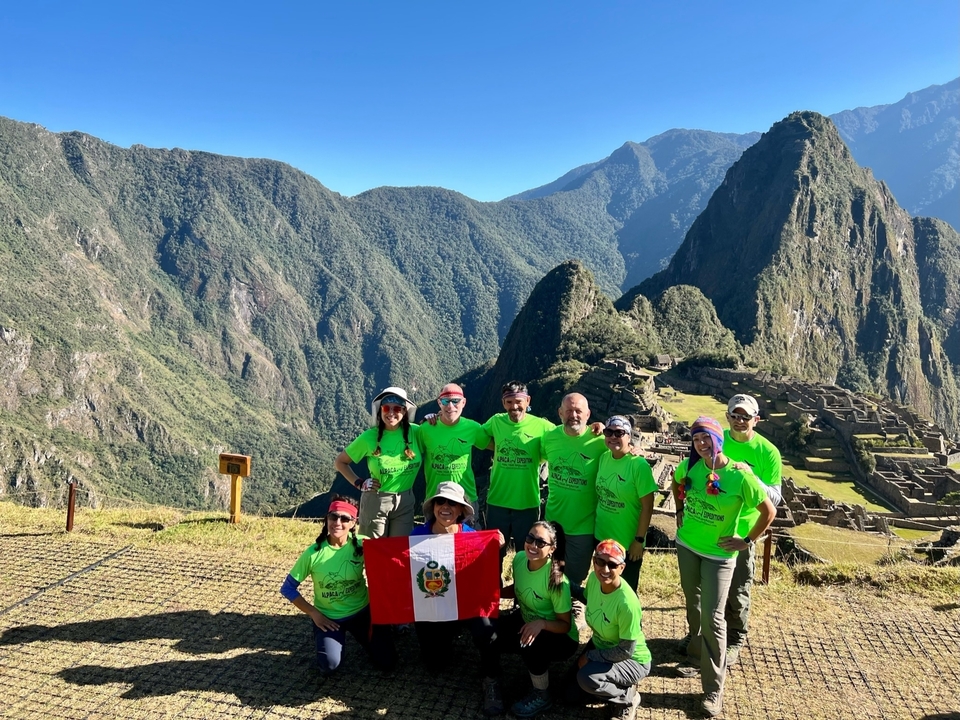 A group posing with the Peruvian flag at Machu Picchu.
