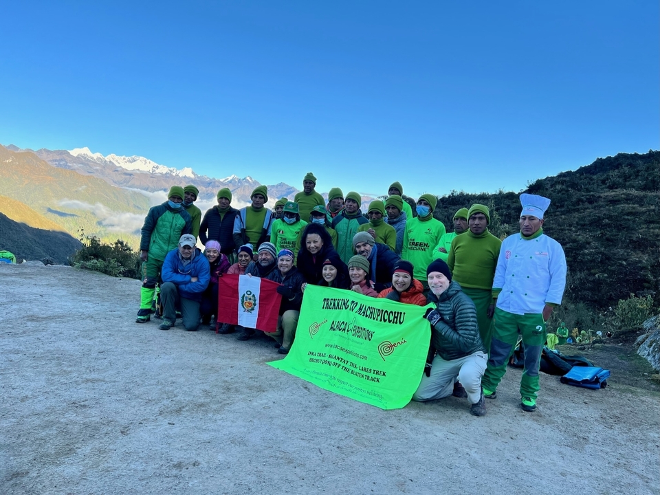 A large group posing with a Peruvian flag at a plateau.