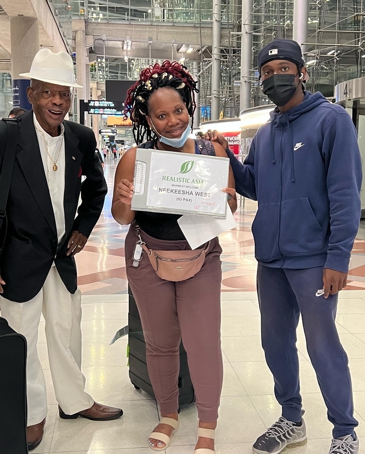 Eine Gruppe von Menschen, die ein Schild an einem Flughafen halten.