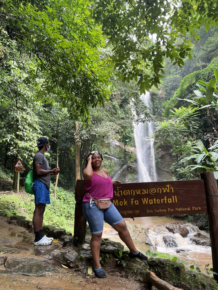 Menschen, die am Fuß eines Wasserfalls posieren.