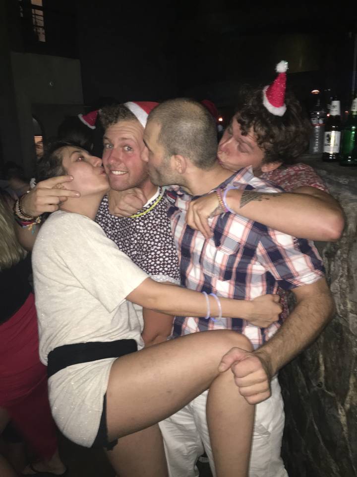 Four people playfully posing in a crowded venue.