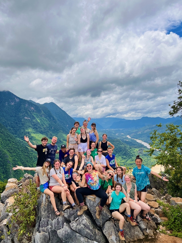Group of people posing with hills and river in background.