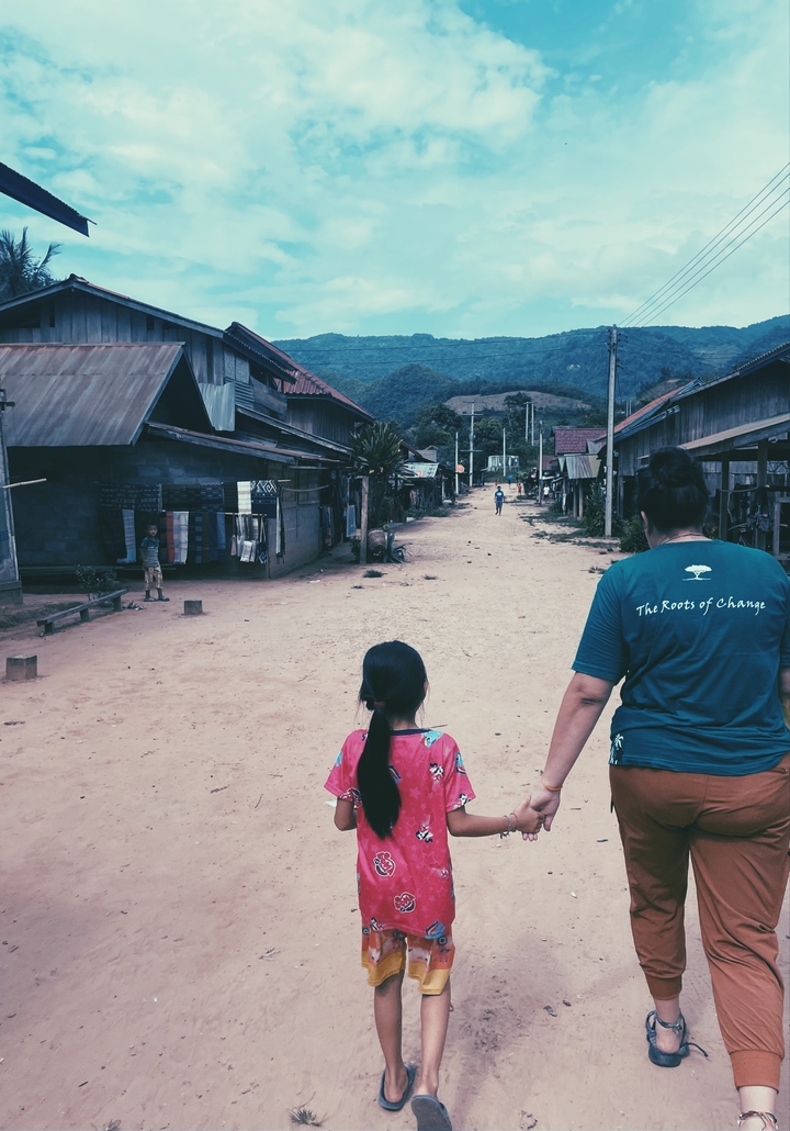 Person walking with a child in a rural village.