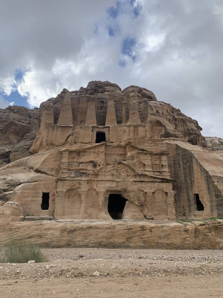 Carved rock formations with cave entrances in a desert.