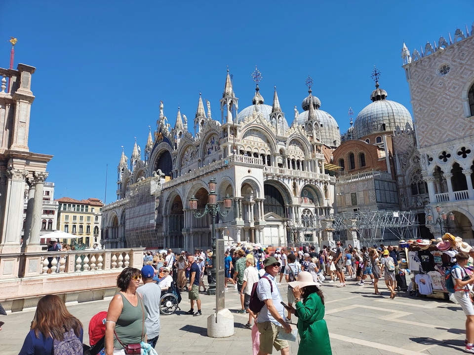 Crowded square with ornate cathedral featuring domes and intricate carvings.