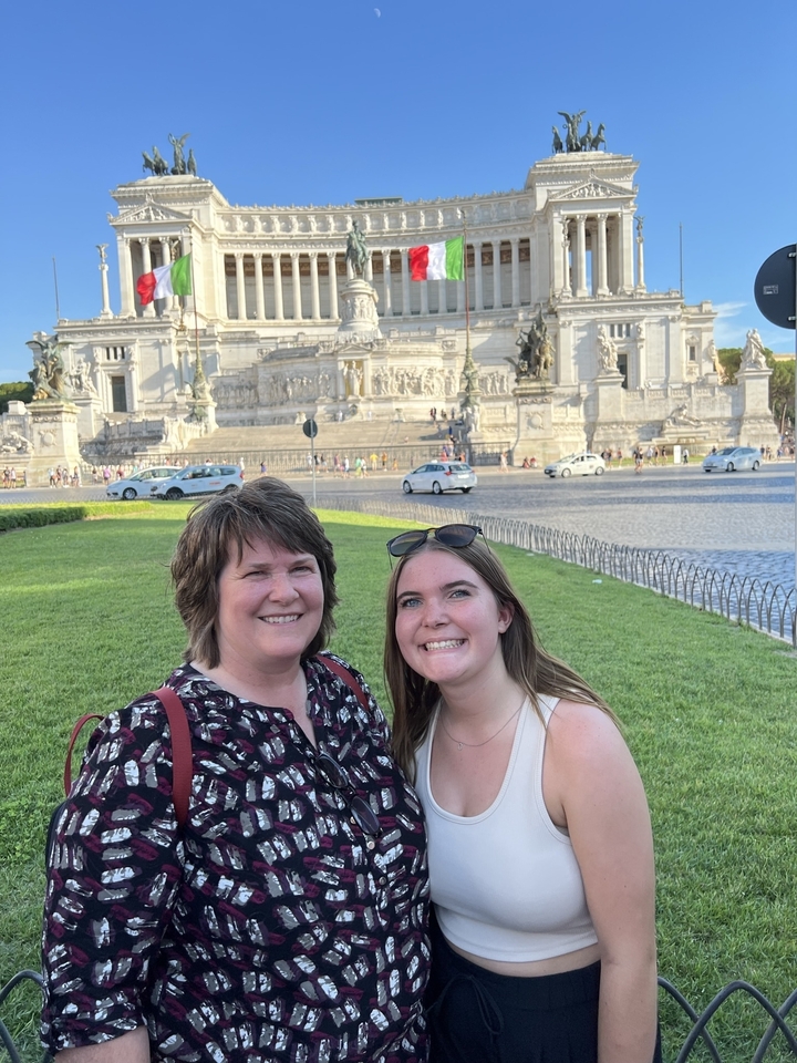 Two women posing in front of a grand white monument.
