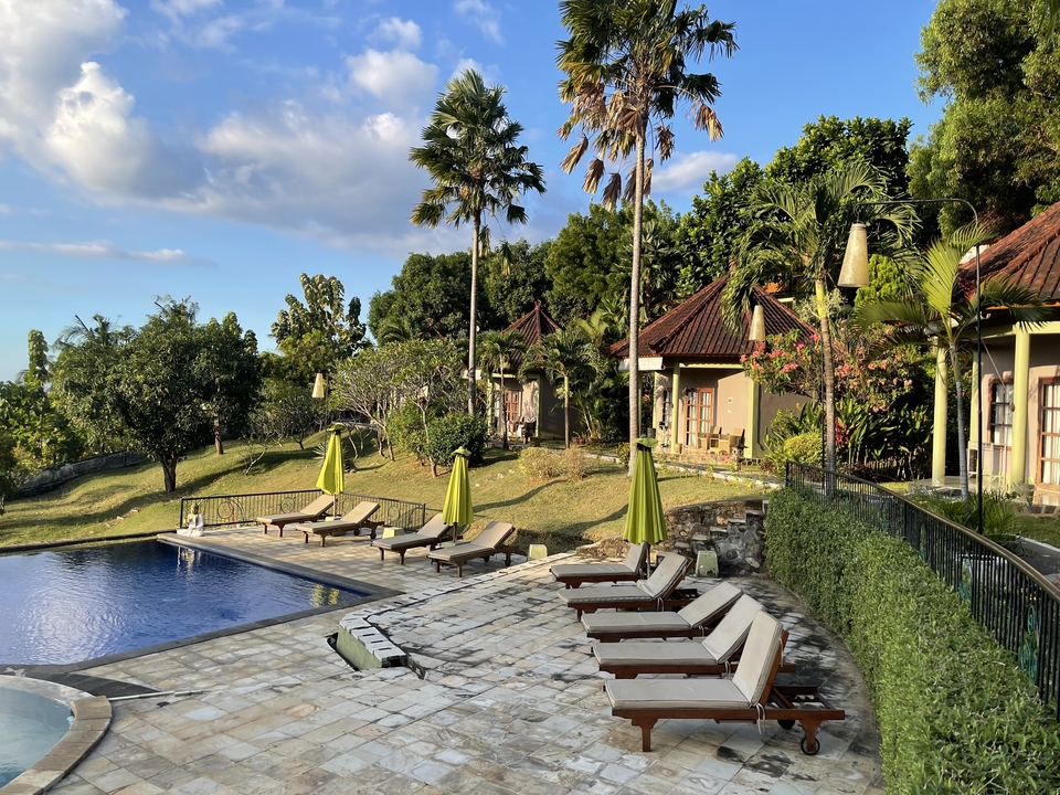 Poolside view with lounge chairs and tropical huts.