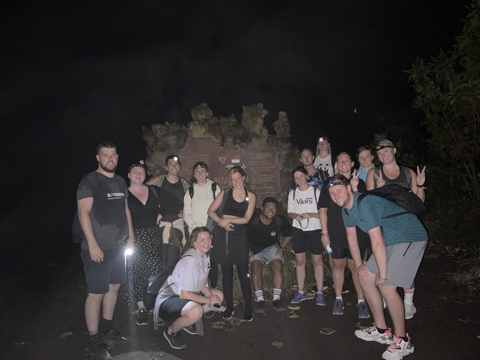 Group of people posing at night with a sign in the background.