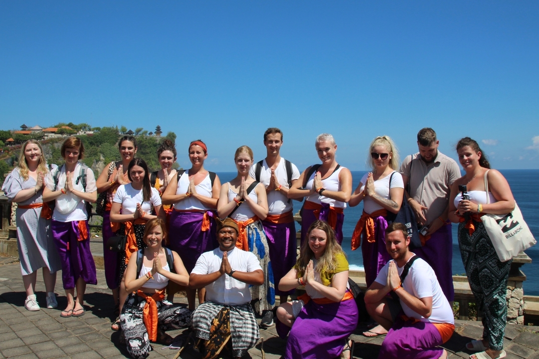 Group of people wearing traditional clothing by a coastline.