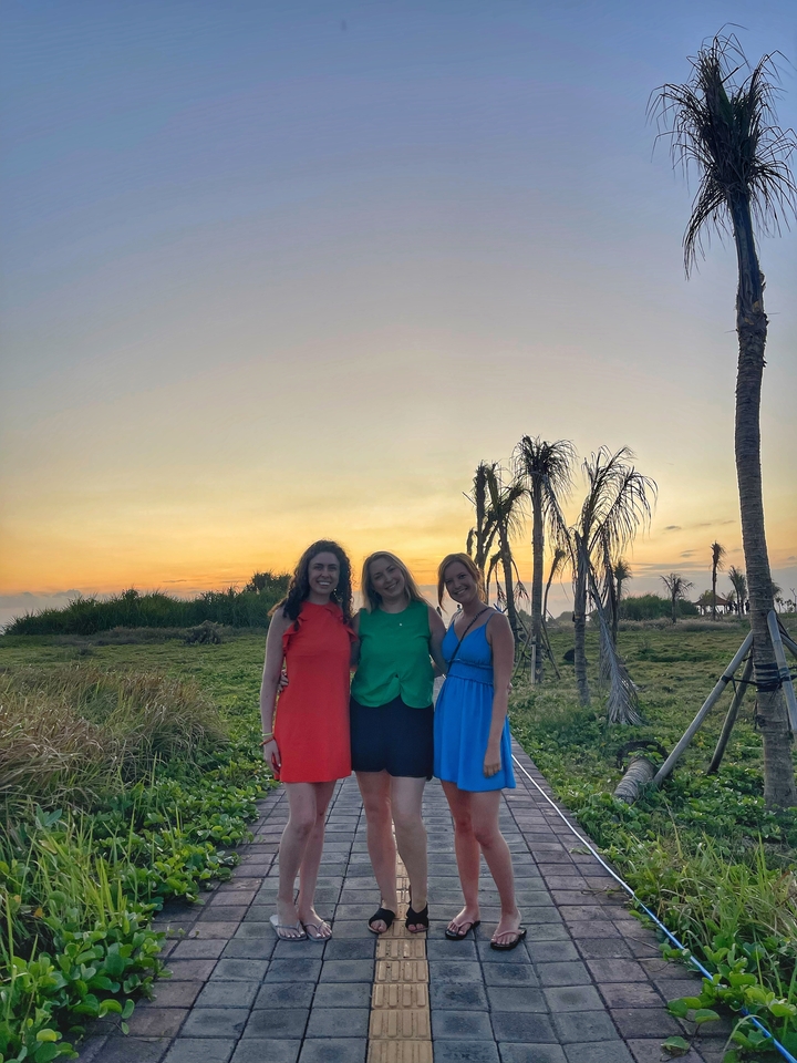 Three women posing at sunset with silhouettes of trees.
