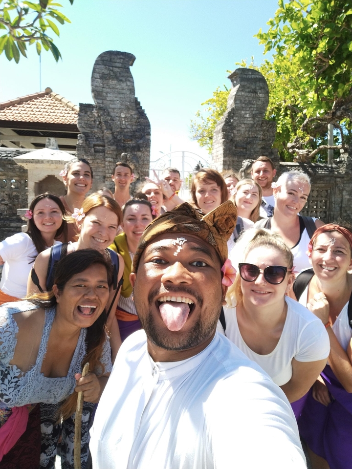 Large group of people smiling at the camera, with floral decorations.