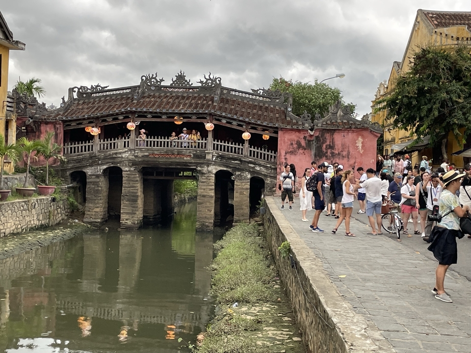 An old Japanese covered bridge with tourists.