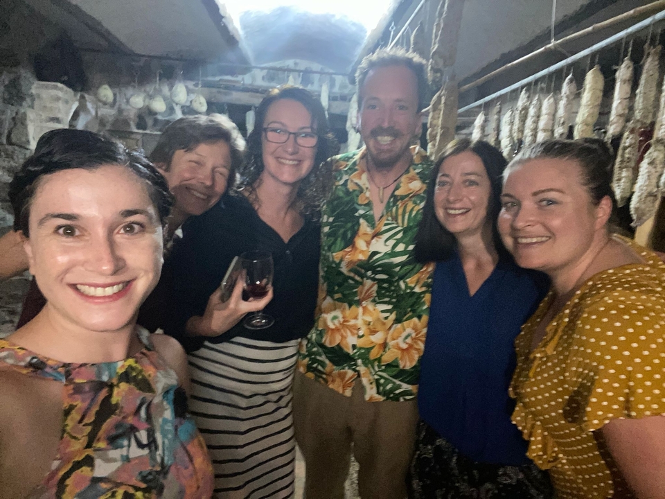 Smiling group of people in a room with hanging sausages.