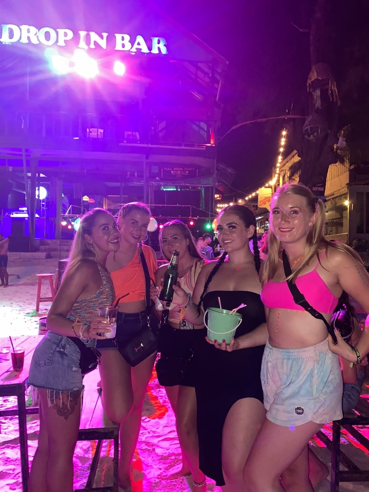 Group of people holding drinks at a night party.