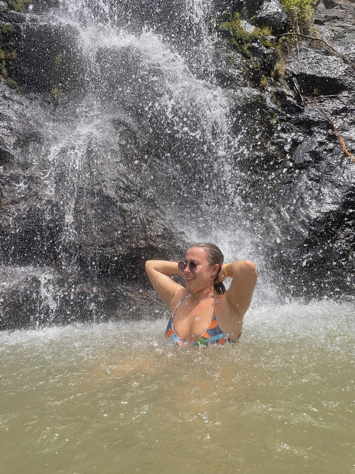 Person standing under a waterfall, enjoying the water.