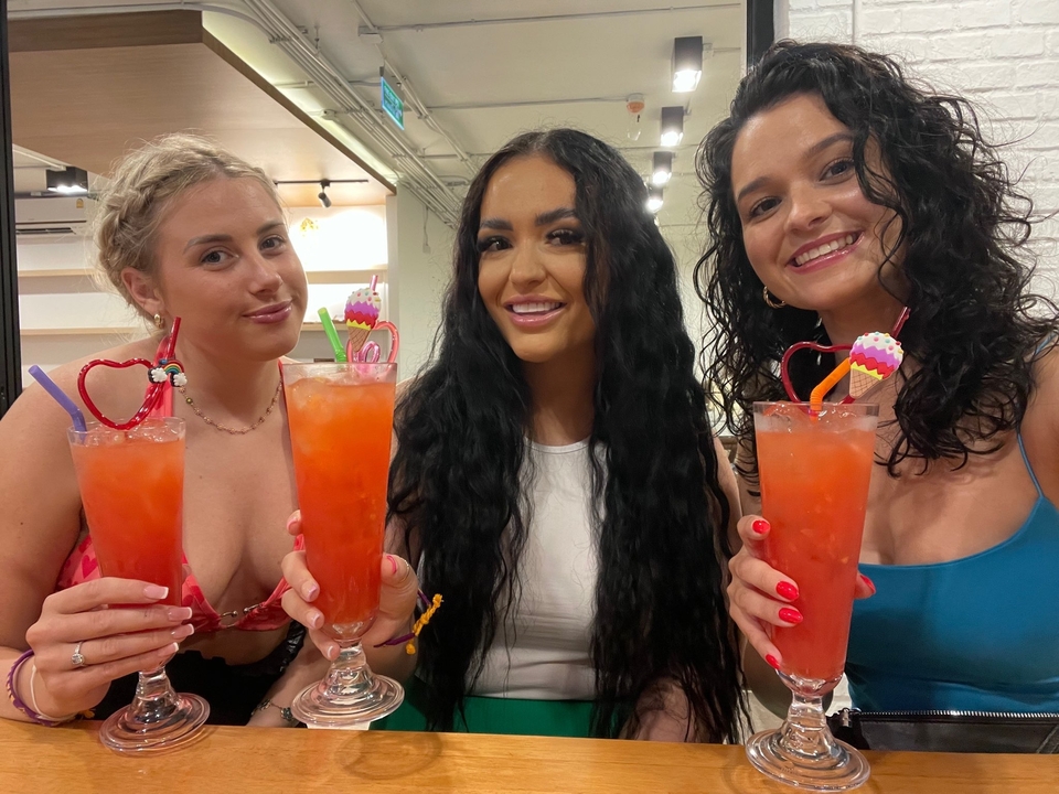 Three women enjoying drinks and smiling indoors.