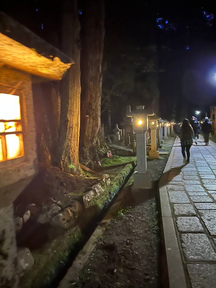 Sentier à travers un cimetière la nuit avec des lanternes.