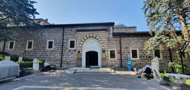 Un bâtiment historique en pierre avec des visiteurs assis à l'extérieur.