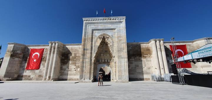 Une porte historique ornée de drapeaux turcs avec quelques personnes devant.