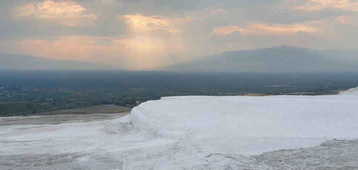 Une vue des terrasses de travertin blanc avec la lumière du soleil perçant à travers les nuages.