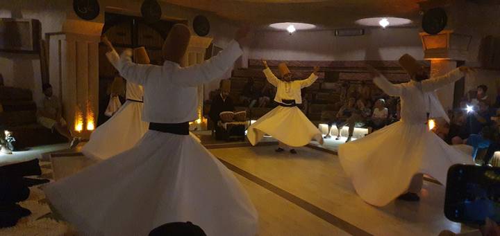 Danseurs exécutant la danse traditionnelle des derviches tourneurs à l'intérieur d'un lieu.