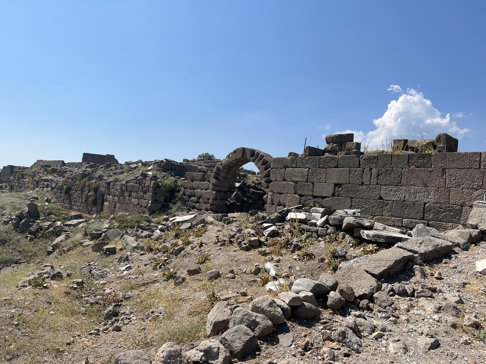 Stone ruins with grassy areas and a partial arch.