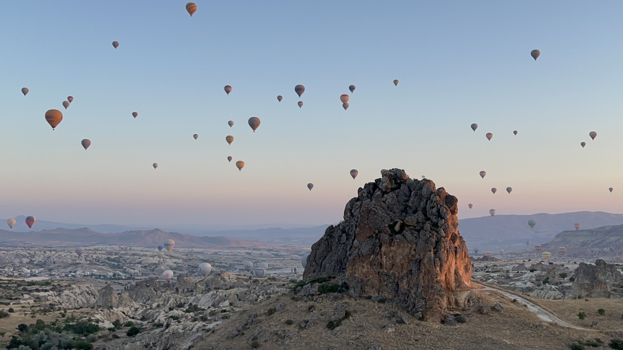 Hot air balloons floating over unique rocky landscapes at sunrise or sunset.